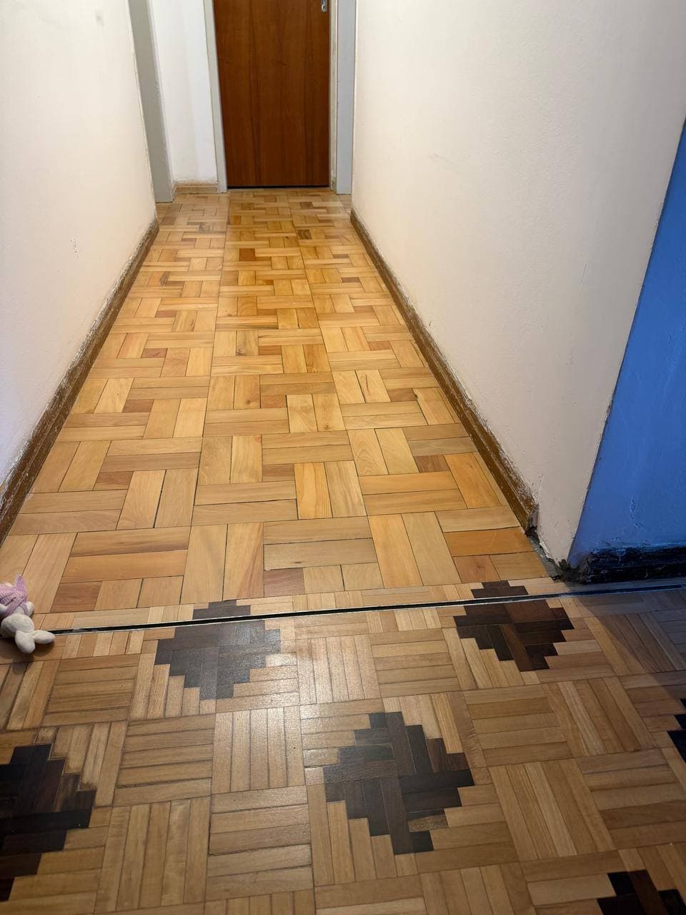 Corredor com piso de taco restaurado, depois da reforma